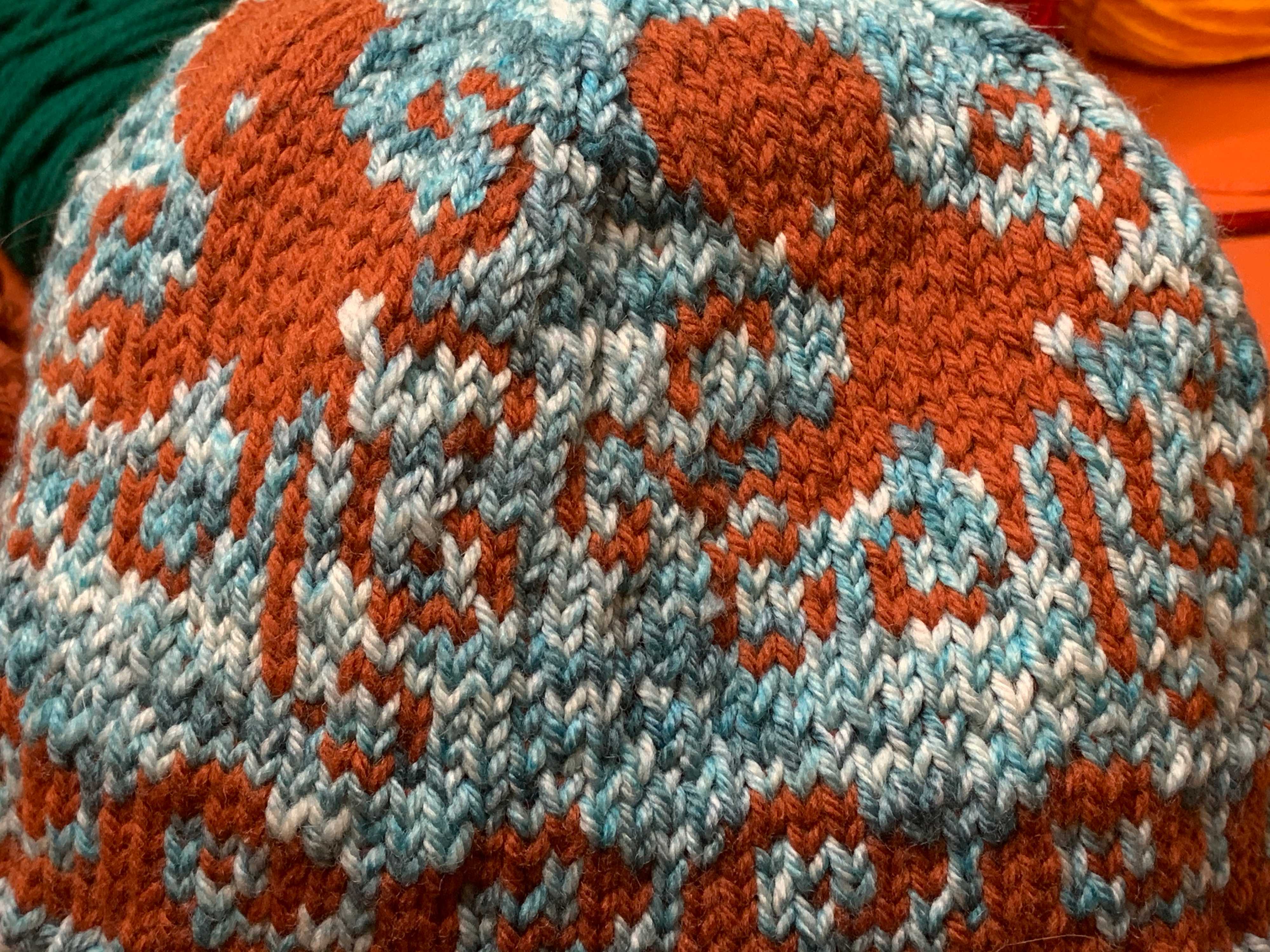 Stranded colorwork hat depicting orange octopi on a blue background. There are large gaps of blue between the octopi.