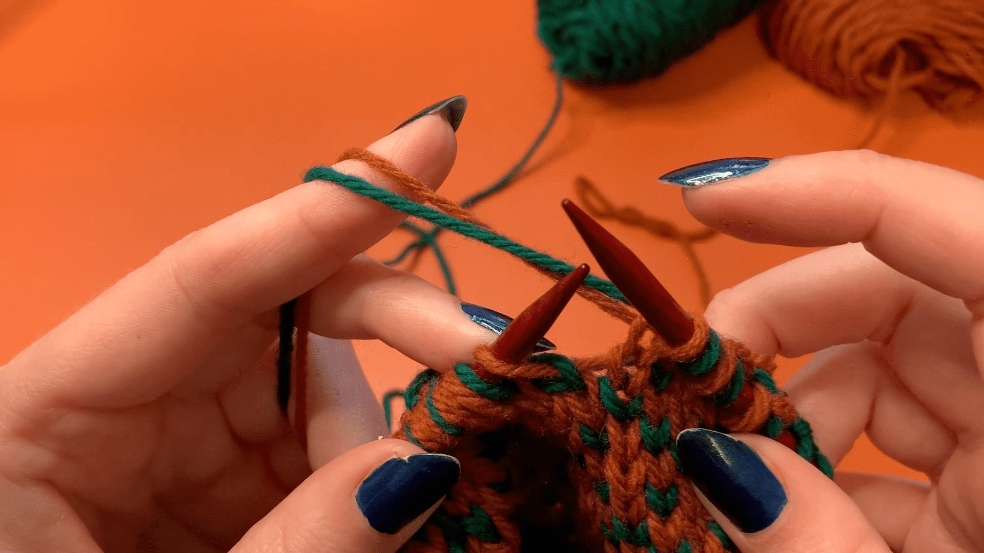 In this photo, the orange yarn is held on top and is dominant.