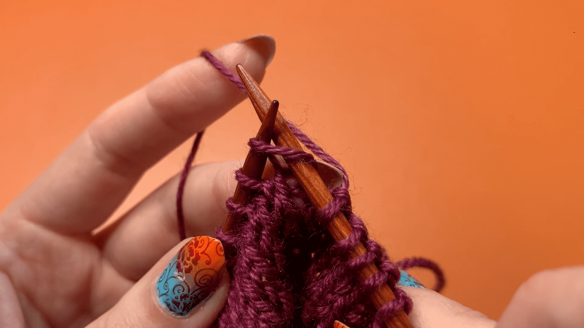 A needle inserted through a stitch as though to knit. The front leg of the stitch is circled.